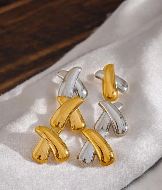 Pair of gold and silver earrings on a white fabric background