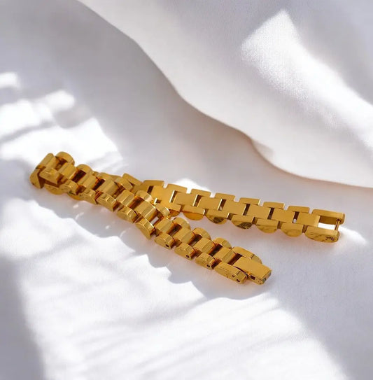 Gold chain bracelet on a white fabric background