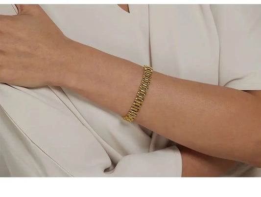 Gold bracelet on a person's wrist with a neutral background