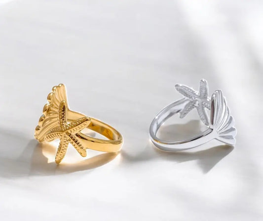 Gold and silver starfish-shaped rings on a light gray background