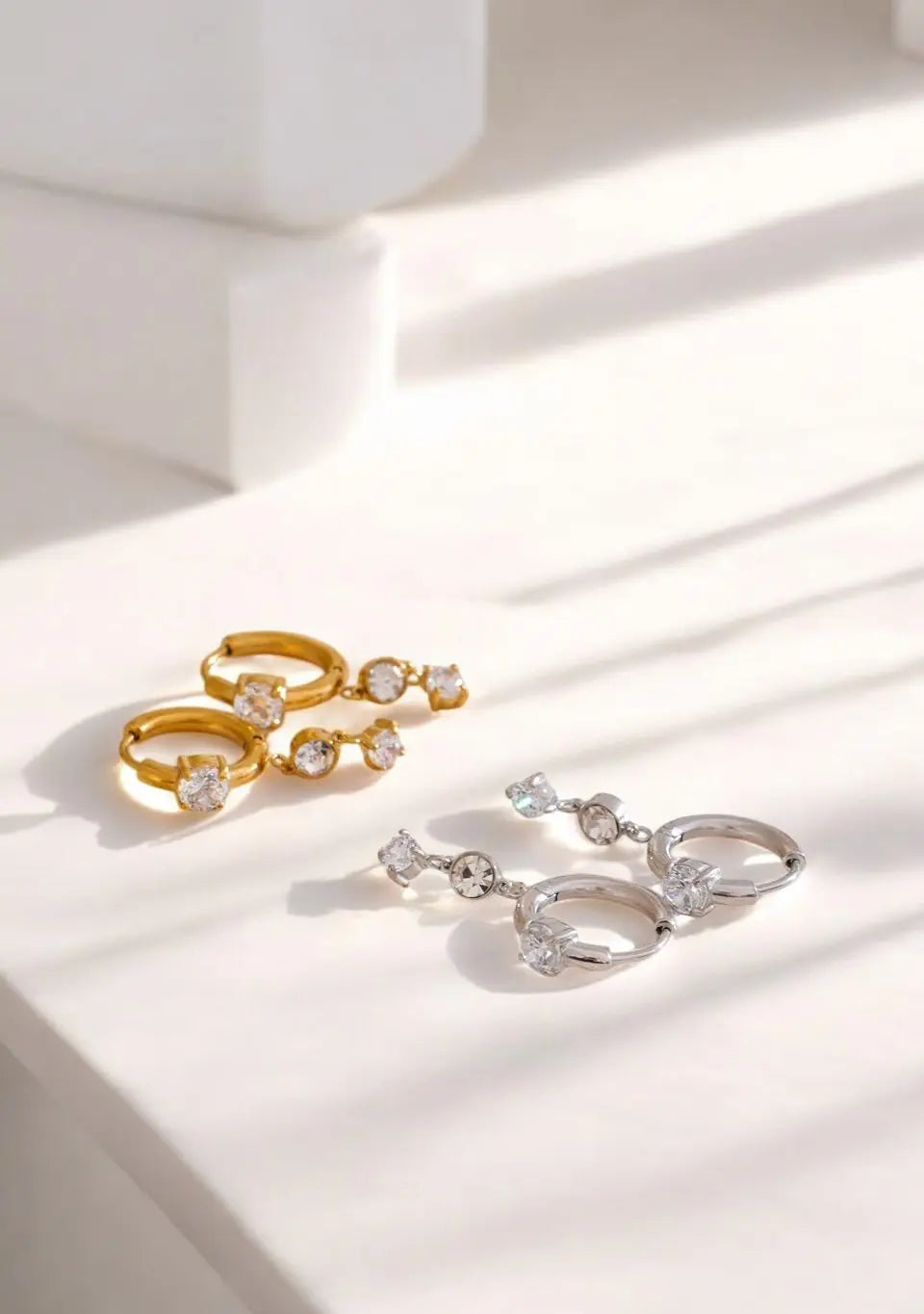 Gold and silver earrings on a light surface with soft shadows
