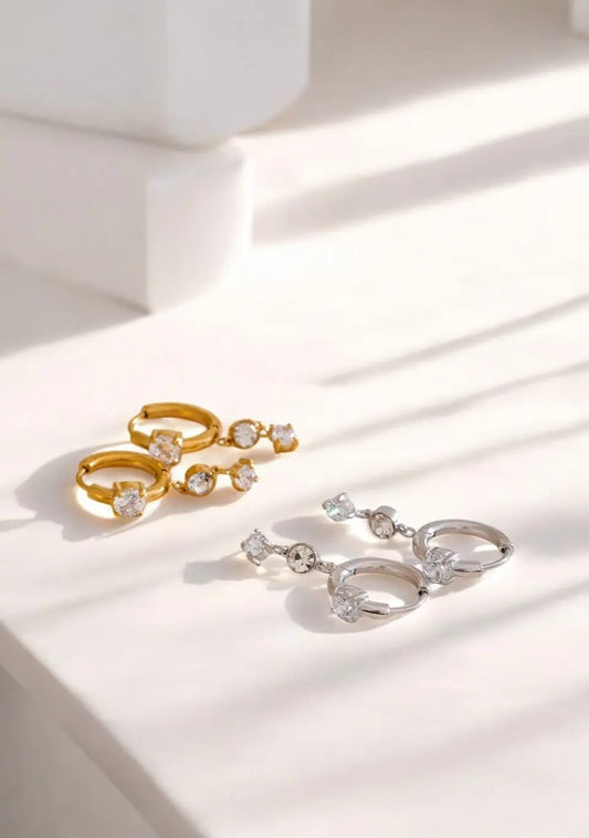 Gold and silver earrings on a light surface with soft shadows