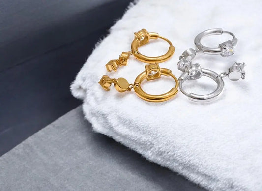 Gold and silver hoop earrings on a white cloth with a gray surface.