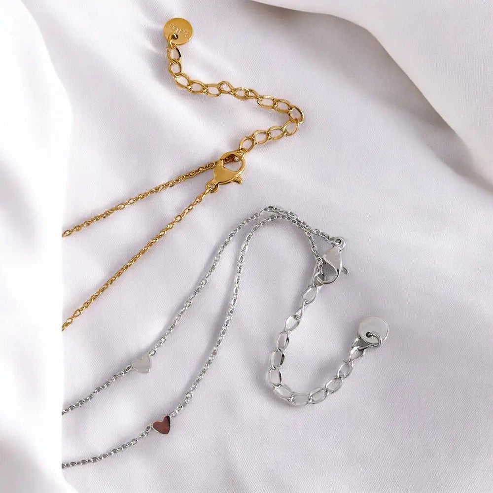 Two gold and silver chains on a white fabric background