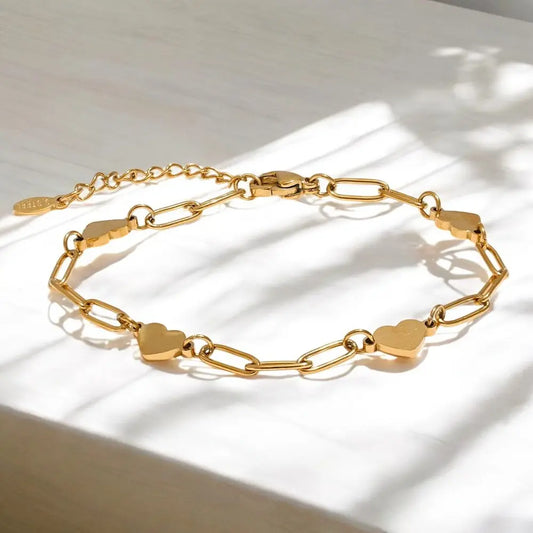 Gold bracelet with heart-shaped charms on a light background