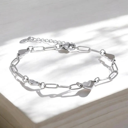 Silver chain bracelet on a light wooden surface with soft shadows