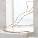 Gold and silver necklace on a clear stand with a marble background