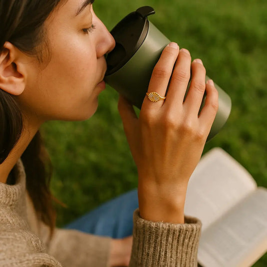 Person drinking from a green insulated mug outdoors