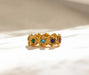 Gold ring with embedded gemstones on a beige background
