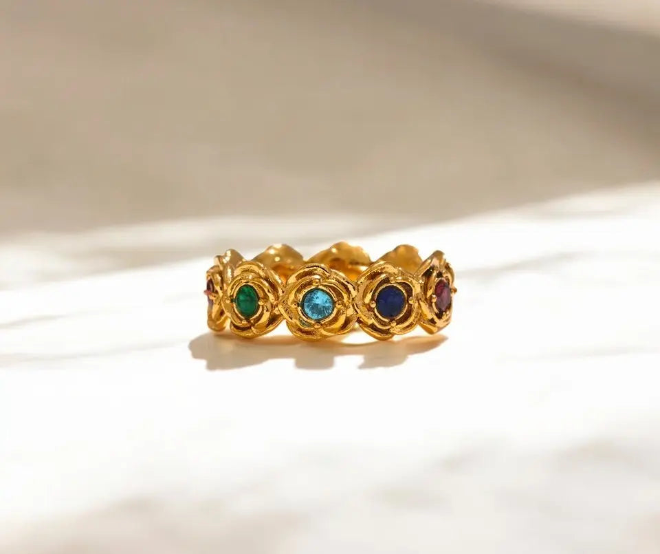 Gold ring with embedded gemstones on a beige background