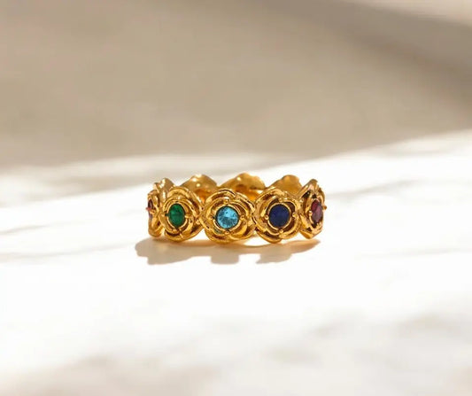 Gold ring with embedded gemstones on a beige background