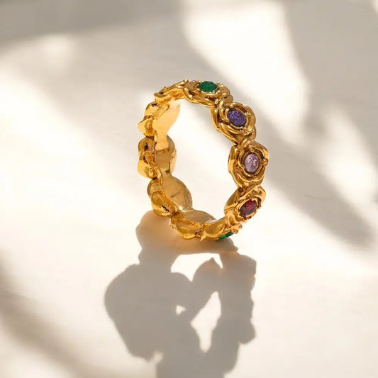 Gold ring with colorful gemstones on a light background