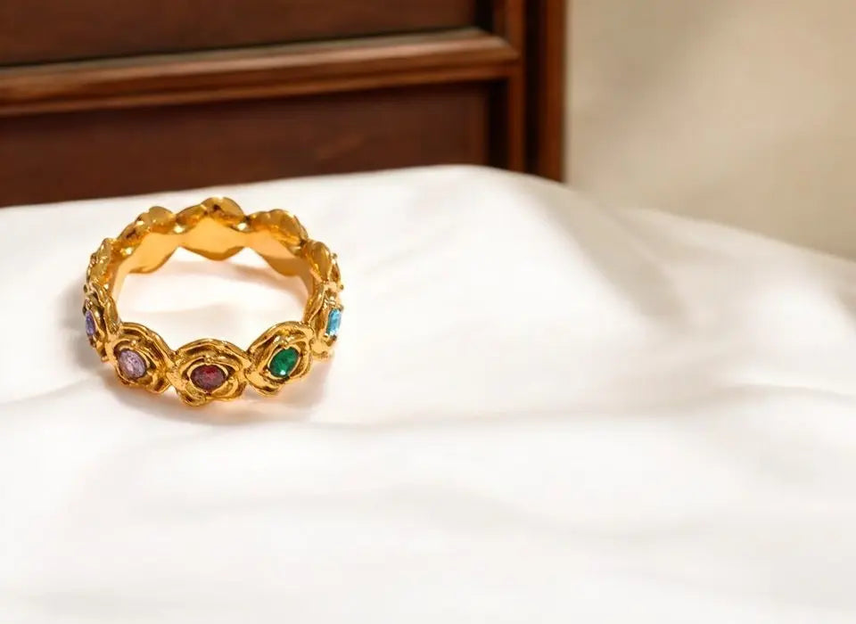 Gold ring with colorful gemstones on a white surface