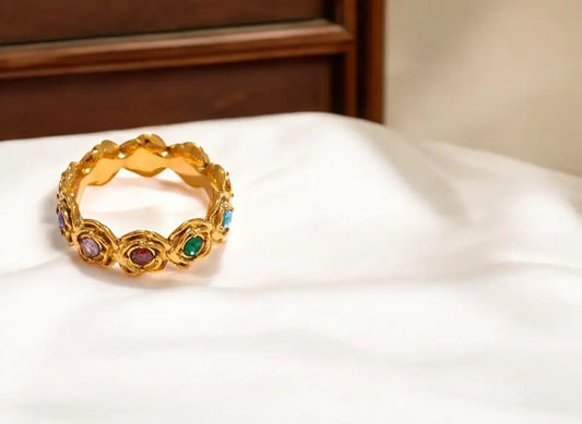 Gold ring with colorful gemstones on a white surface