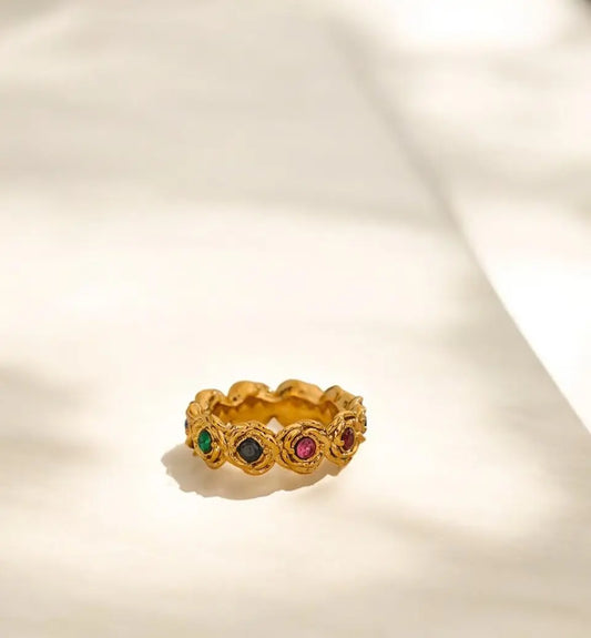 Gold ring with colored gemstones on a light beige background
