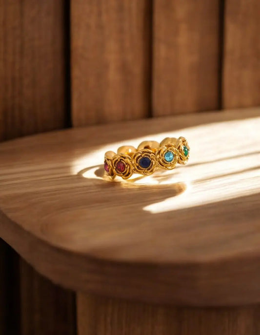 Gold ring with colored gemstones on a wooden surface