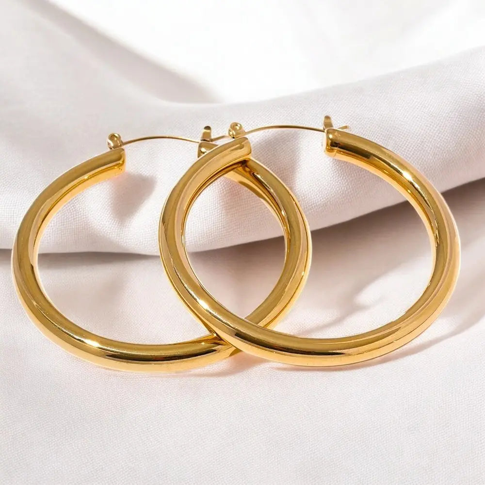 Gold hoop earrings on a white fabric background