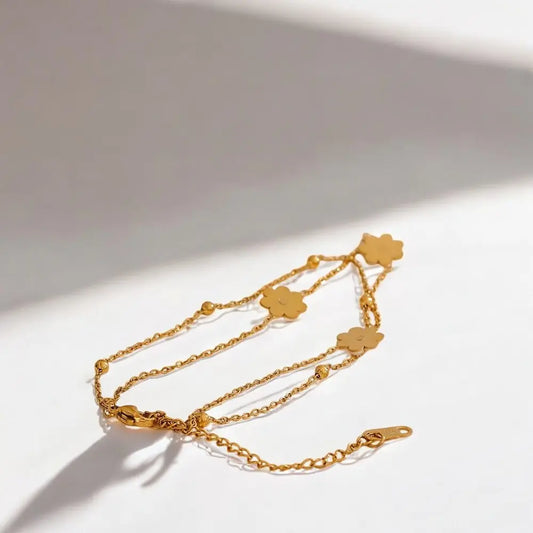 Gold bracelet with clover-shaped charms on a white background