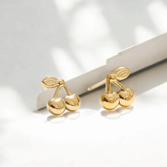 Gold cherry-shaped earrings on a light background
