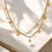 Gold chain necklace with square pendants on a light background
