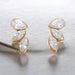 Gold earrings with clear gemstones on a light gray background