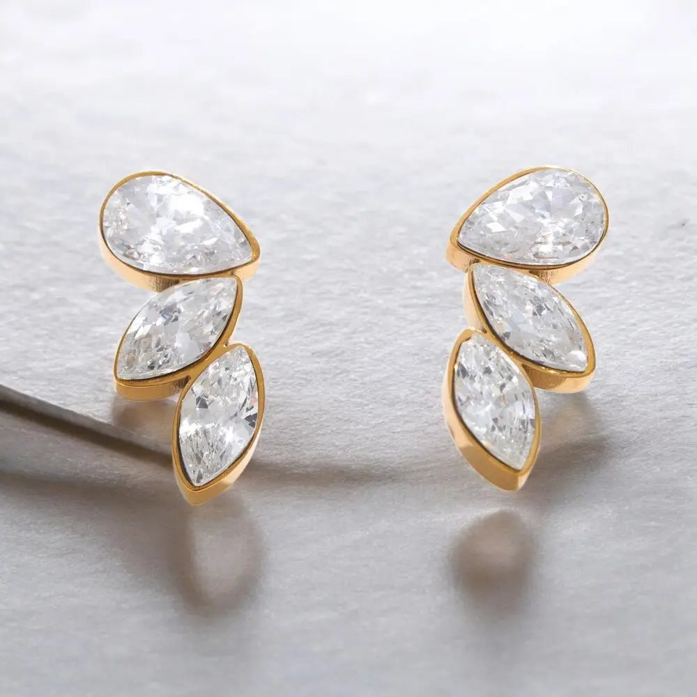 Gold earrings with clear gemstones on a light gray background