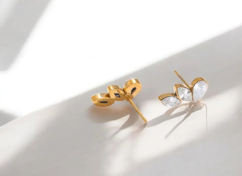 Gold bow-shaped earrings on a light background