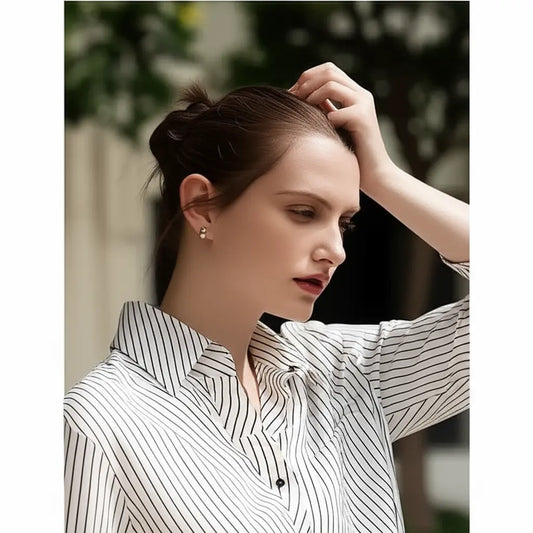 Woman adjusting her hair with a blurred outdoor background