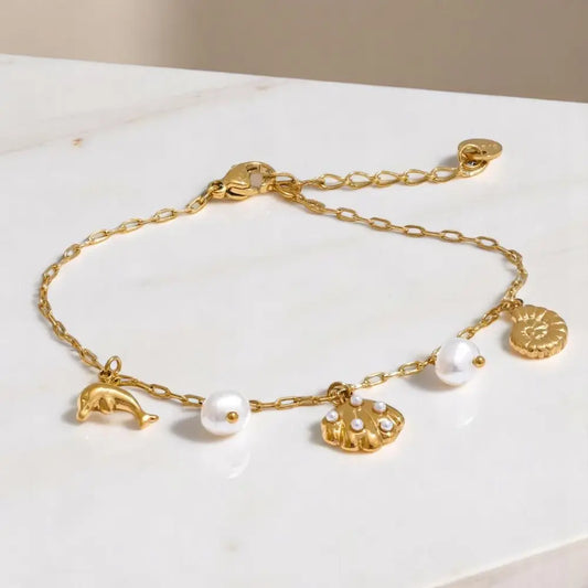 Gold bracelet with various charms on a white surface