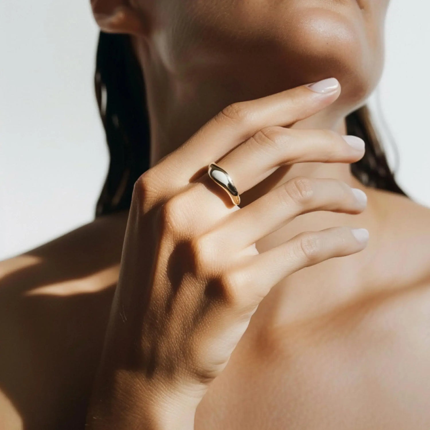 Close-up of a hand wearing a gold ring with a blurred background