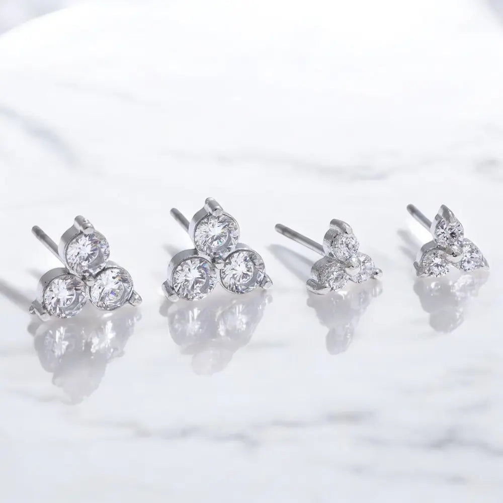 Set of four silver stud earrings with clear gemstones on a white background
