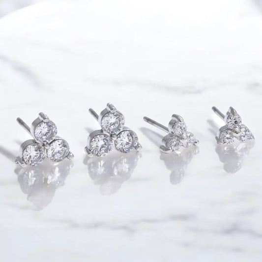 Set of four silver stud earrings with clear gemstones on a white background