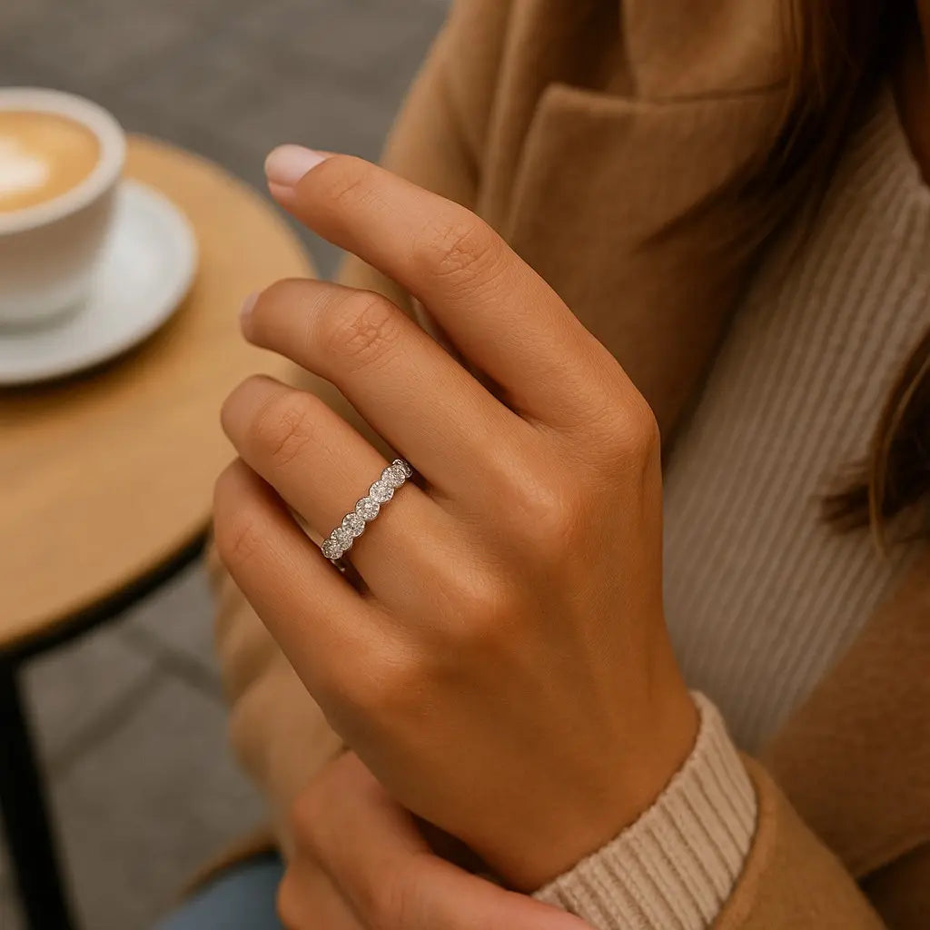 Hand wearing a diamond ring with a blurred coffee cup in the background