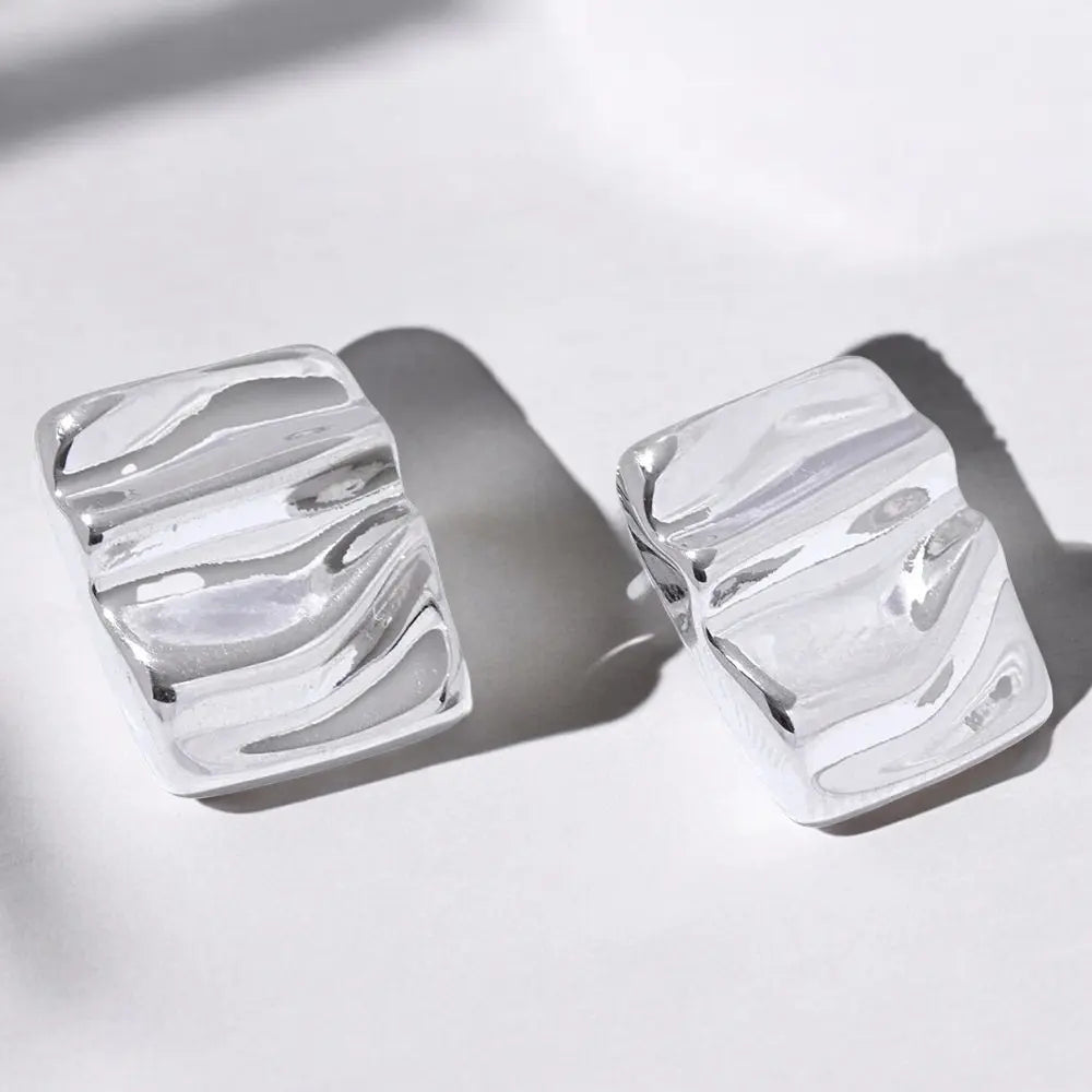 Pair of silver earrings with a marbled design on a light background