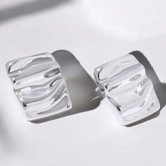 Pair of silver earrings with a marbled design on a light background