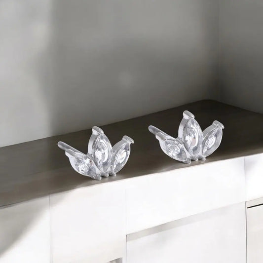 Two crystal peacock decorations on a reflective surface with a neutral background