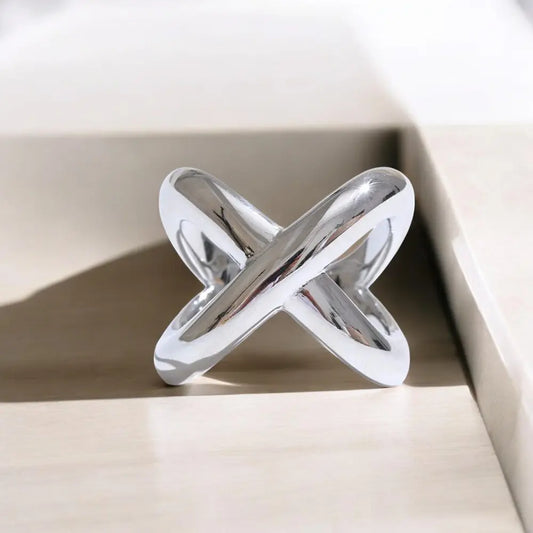 Silver ring with a unique design on a beige surface