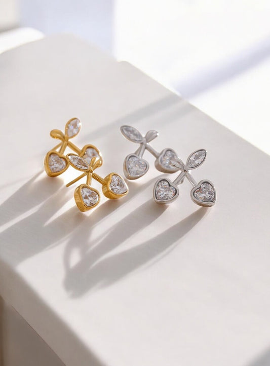 Gold and silver earrings on a white surface with a soft light background