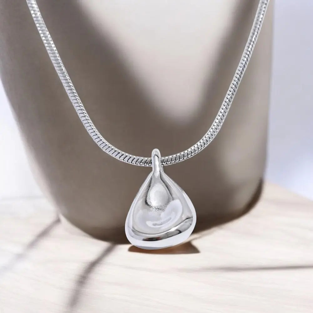 Silver teardrop pendant necklace on a neutral background