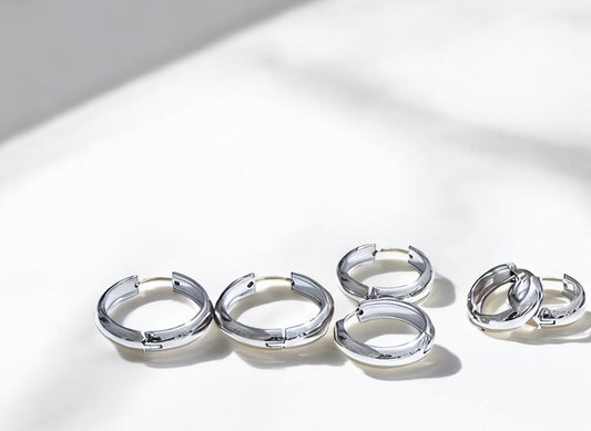 Set of silver hoop earrings on a reflective surface