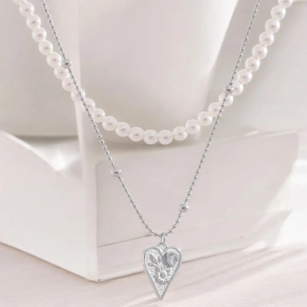 Necklace with a heart-shaped pendant and pearl necklace on a white surface