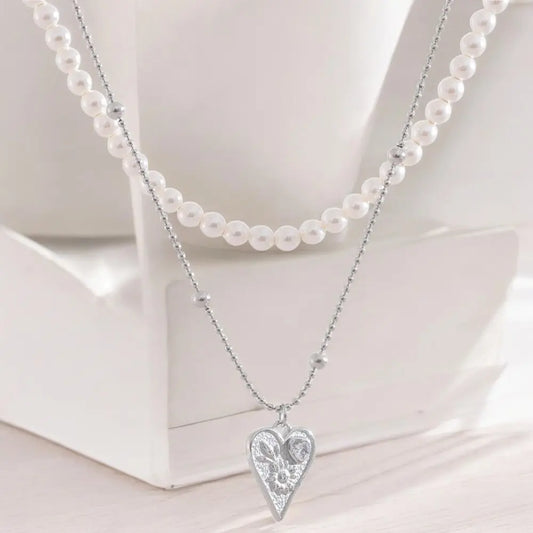Necklace with a heart-shaped pendant and pearl necklace on a white surface