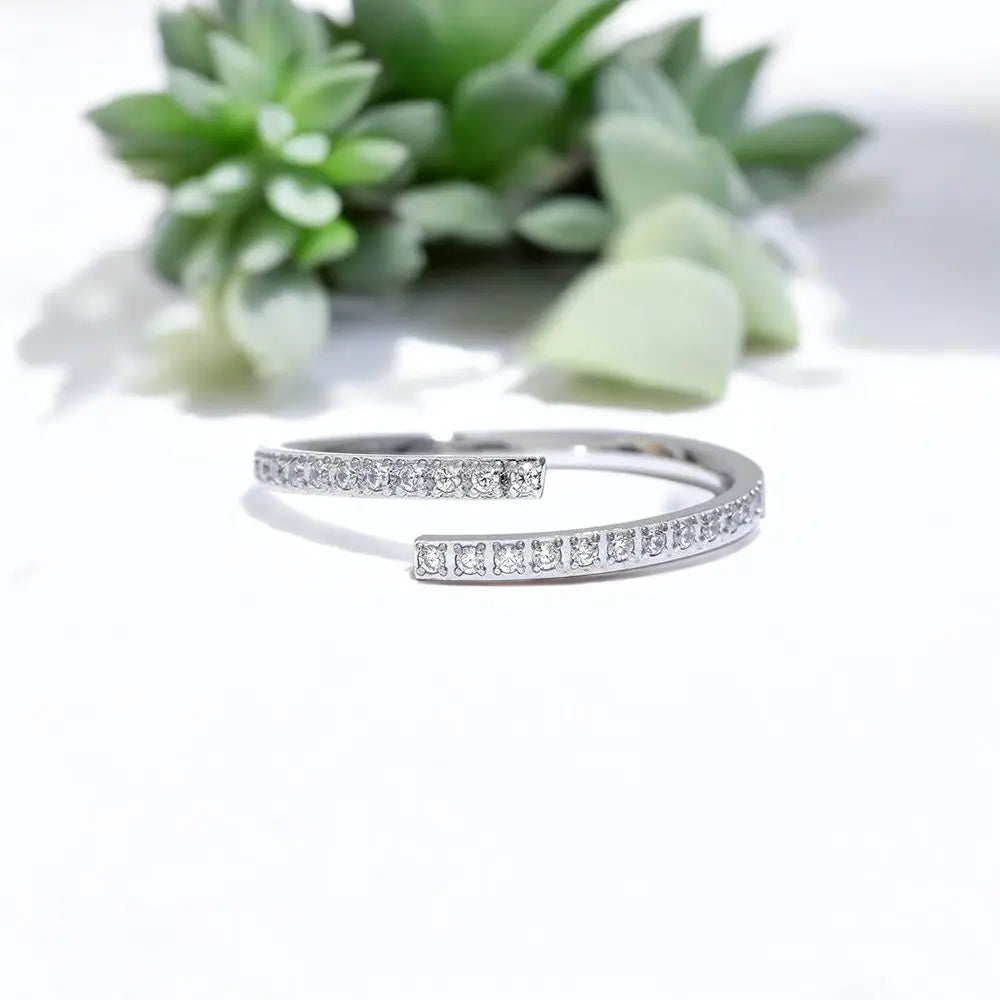Silver bracelet with small diamonds on a white background with green plants.
