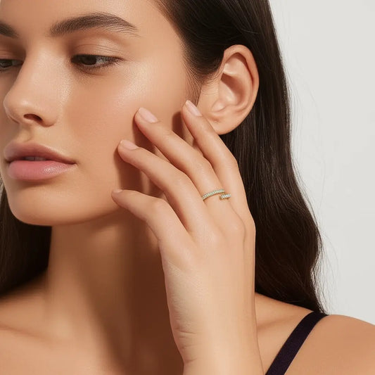 Close-up of a woman's face with one hand touching her cheek, wearing a delicate ring.