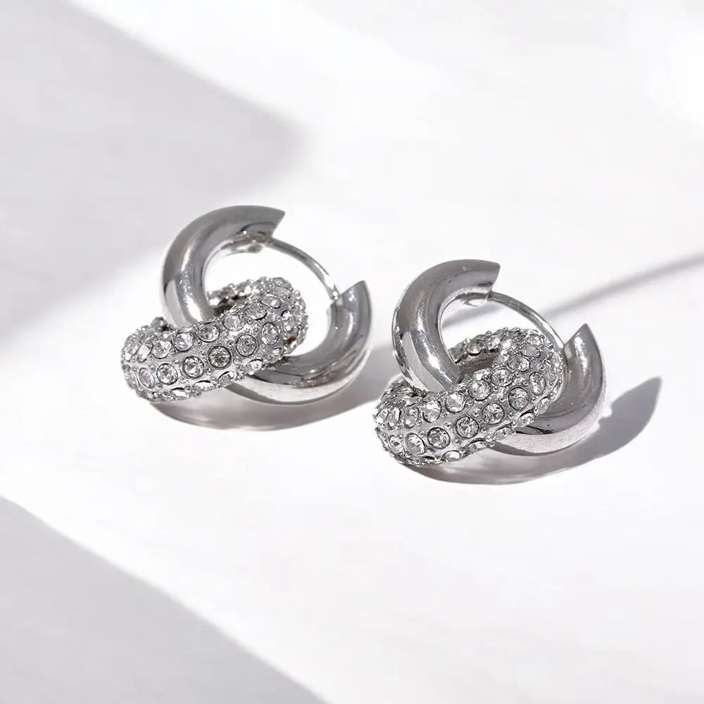 Pair of silver hoop earrings with embedded stones on a light background