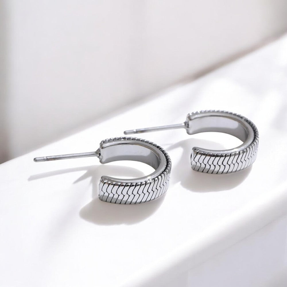Silver hoop earrings on a white surface with a soft shadow