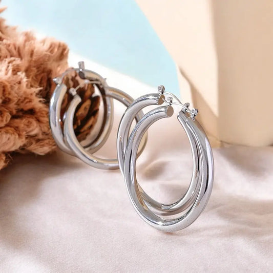 Silver hoop earrings on a soft surface with a neutral background