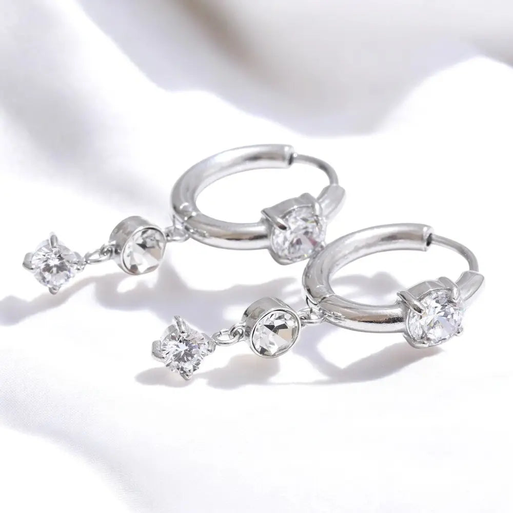 Silver hoop earrings with clear gemstones on a white background