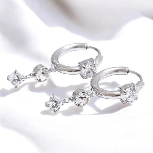 Silver hoop earrings with clear gemstones on a white background