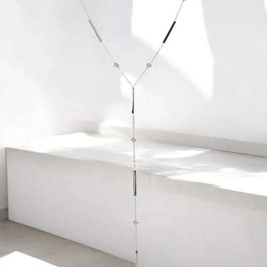 Long necklace with beads hanging against a white background